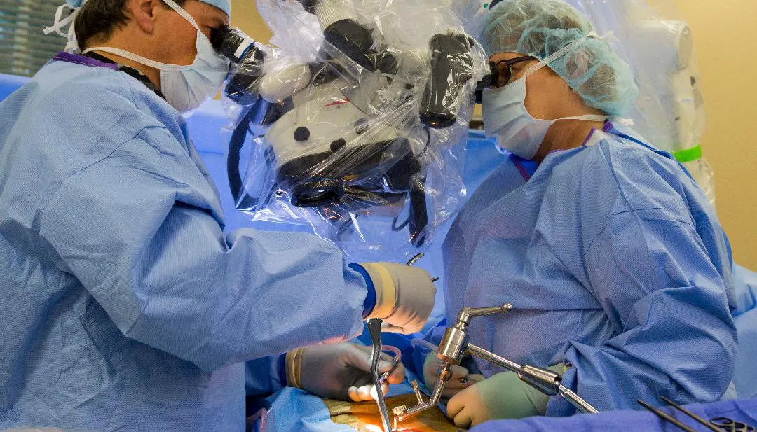Spine surgeons operating under a surgical microscope, Wiggins Medical spine surgery instruments